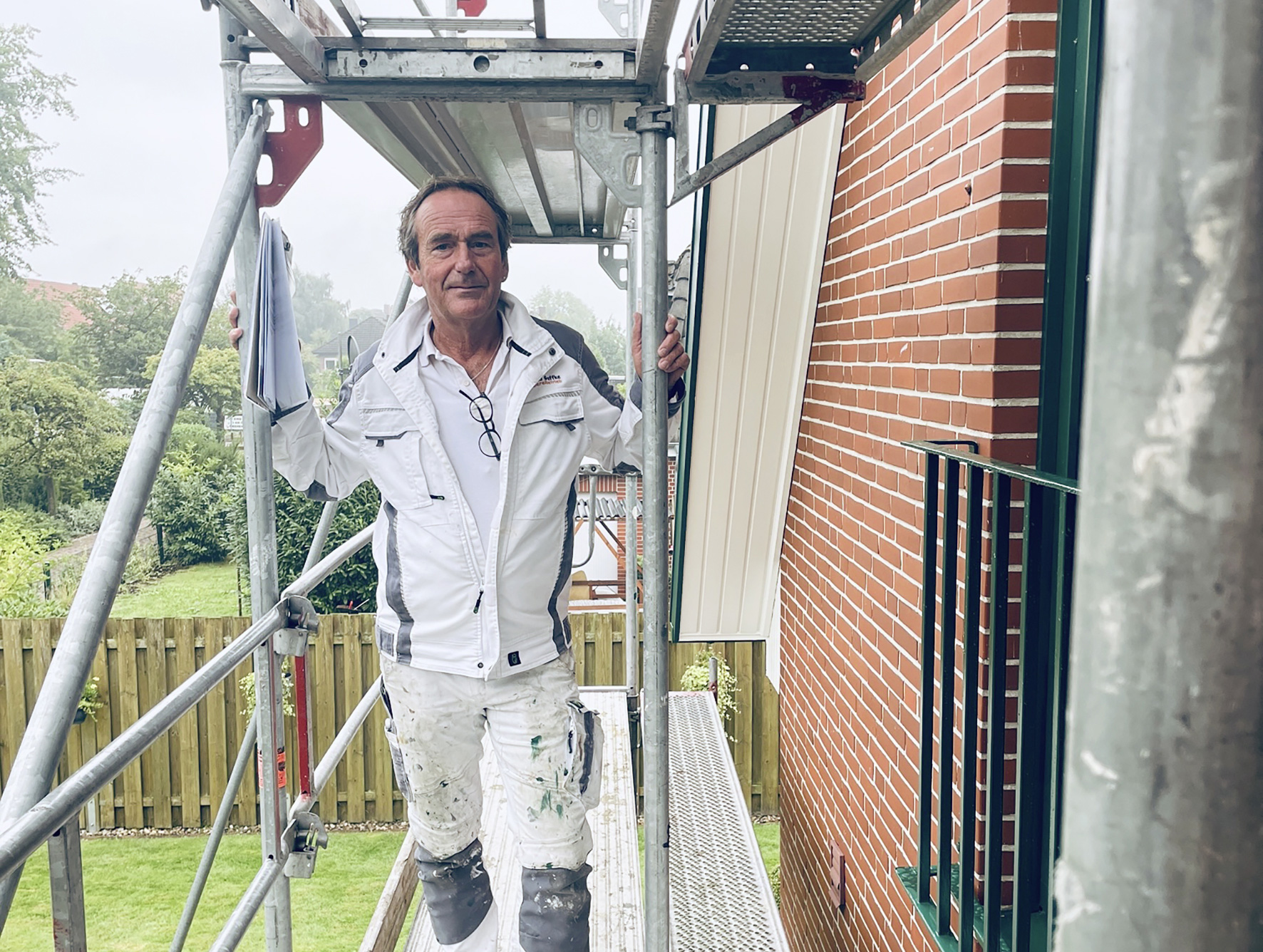 Porträt von Bernd Geffke vor einem Haus mit Baugerüst.