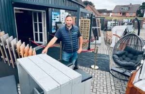 Ein Mann in einer Gartenmöbelausstellung von Heitmann & Junge mit verschiedenen Outdoor-Möbeln.