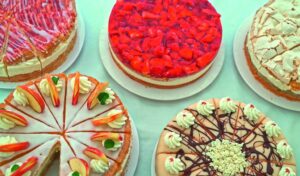 Mehrere Obst- und Sahnetorten auf Tellern, von oben fotografiert